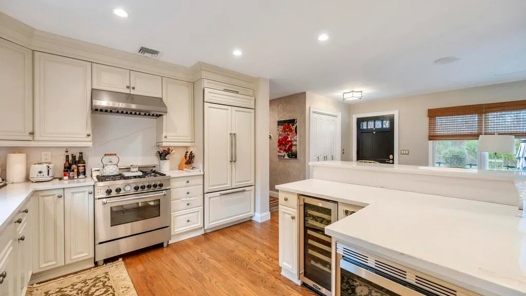 A bright kitchen with light cabinetry, stainless steel appliances, and a large island.