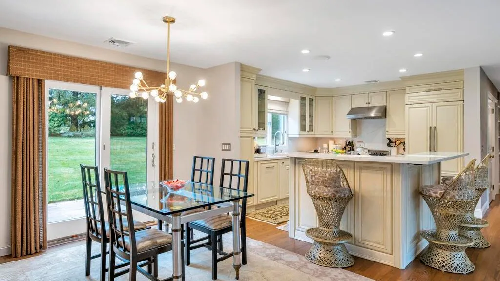 A dining area with a glass table beside an open kitchen.