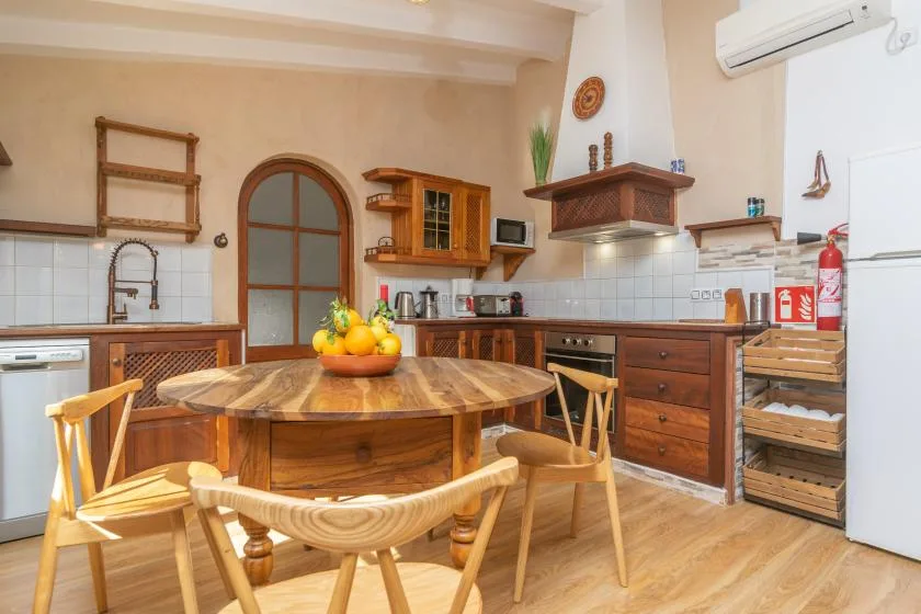 A kitchen with a round wooden dining table and chairs in the foreground.