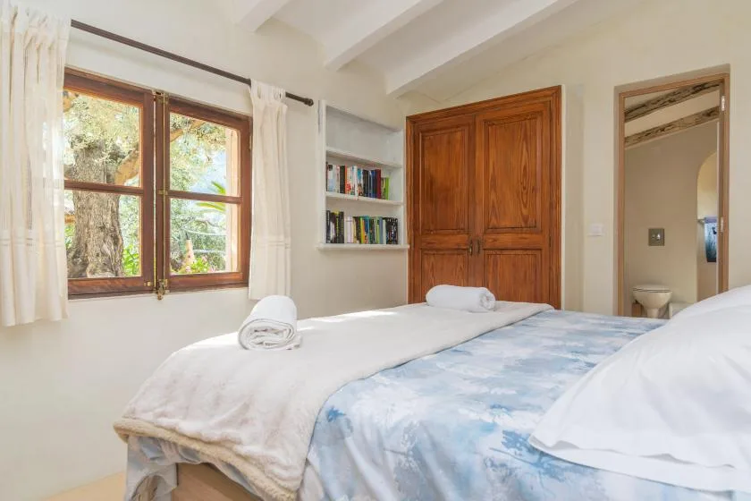 A bedroom with a wooden wardrobe, a window, and beds with white linens.