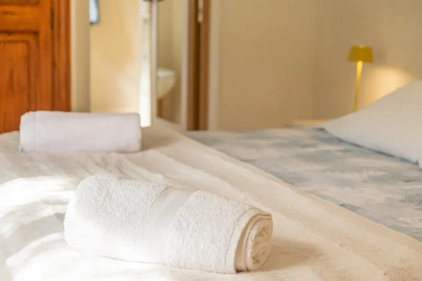 A bedroom with neatly made beds and folded white towels.