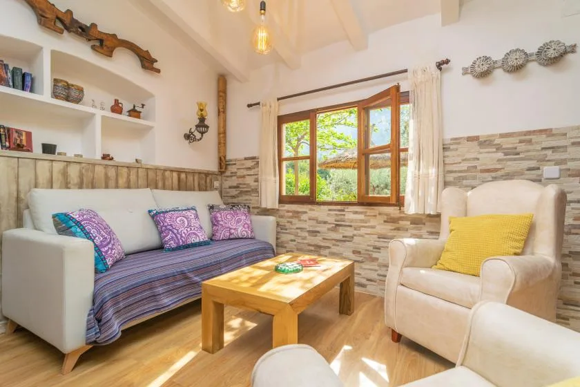 A living room with seating arranged around a wooden coffee table and a window.