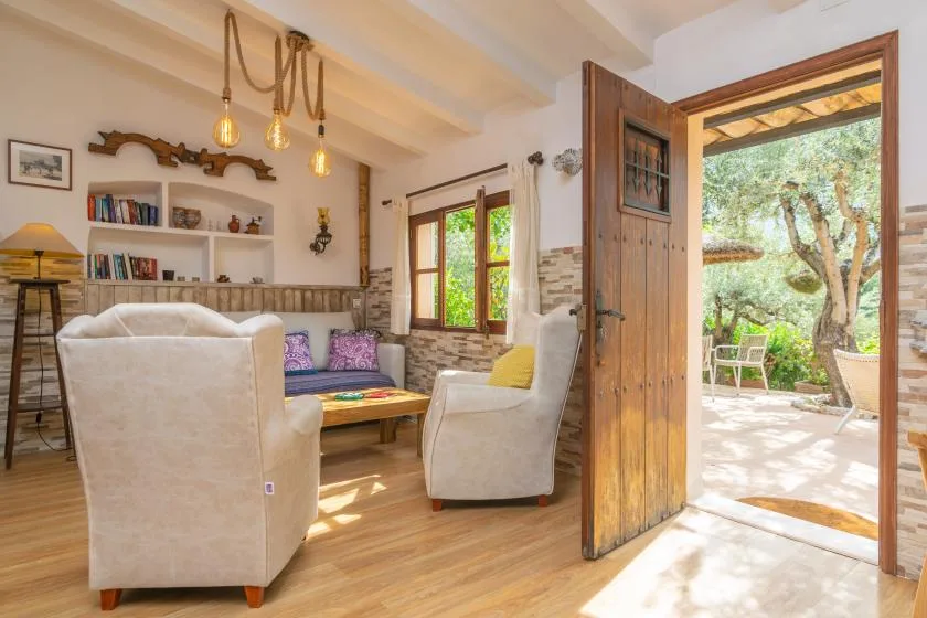 A living room with upholstered seating, a low table, and an open door to a patio.
