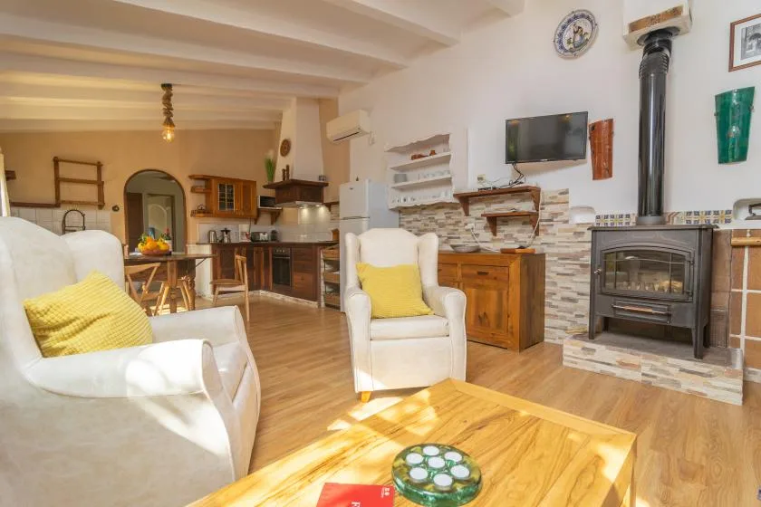 A living room with seating, a wooden coffee table, and a stove beside the kitchen.