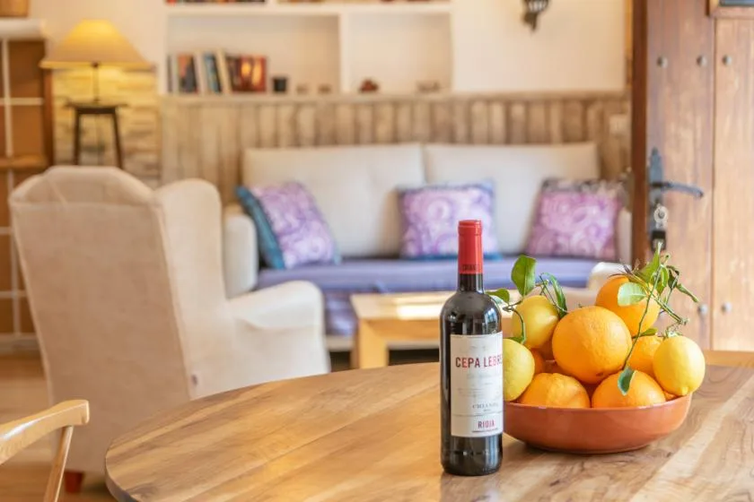 A cozy living room with a wooden table, a bowl of oranges, and a sofa.