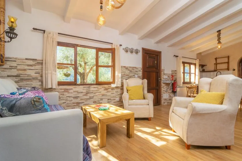 A bright living room with cushioned seating, a wooden coffee table, and large windows.