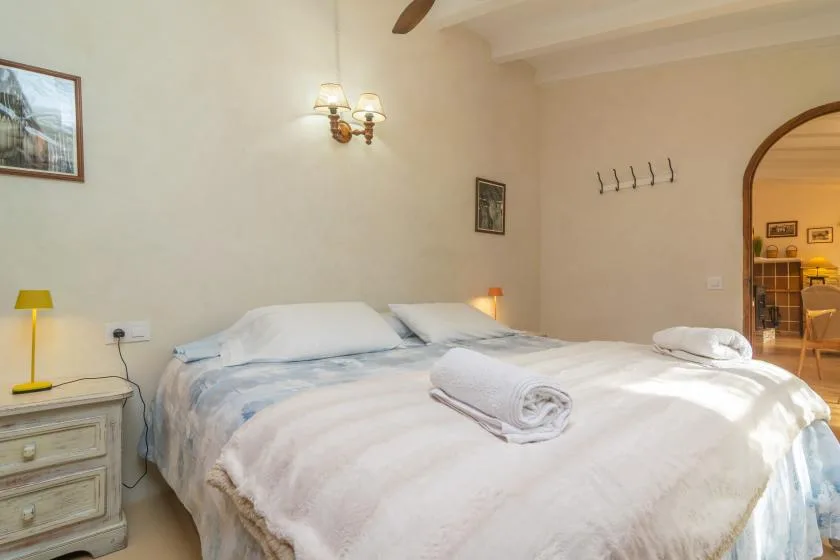 A bedroom with a large bed, white bedding, and folded towels.