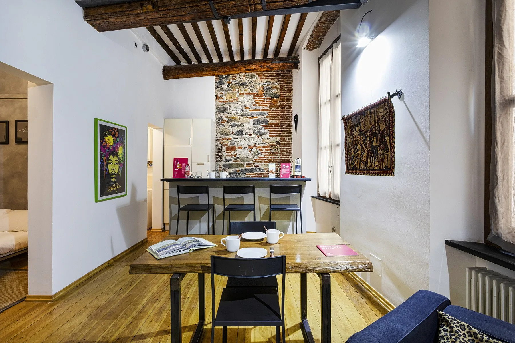 Comedor con una mesa de madera, sillas y una barra bajo vigas expuestas.