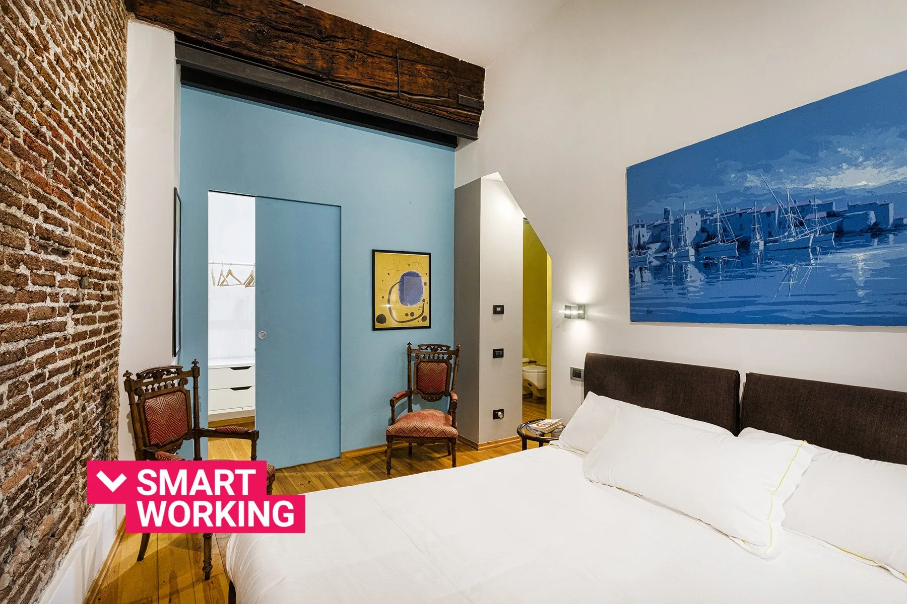 A bedroom with a large bed, blue sliding door, and exposed brick wall.