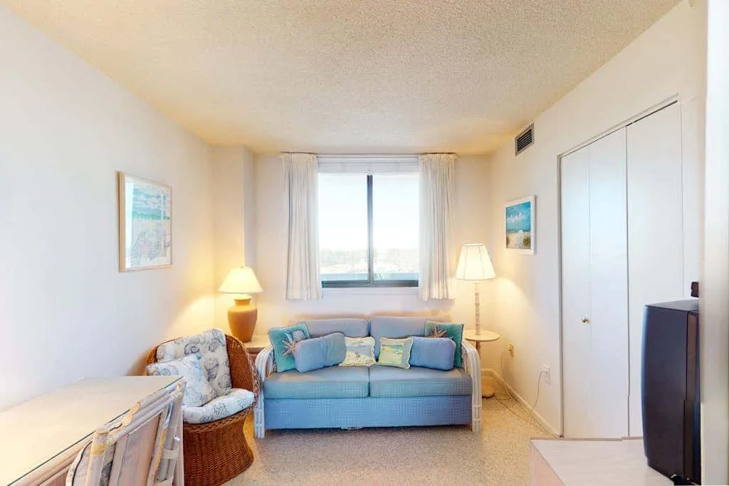 A bright living room with a blue sofa beneath a large window.