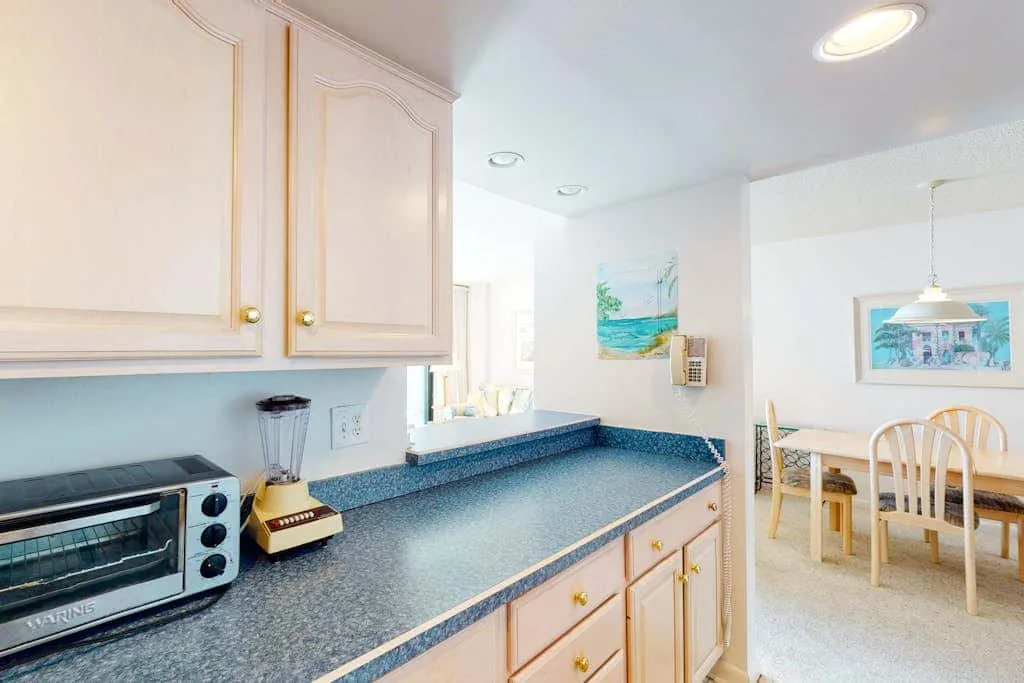 A kitchen with a long countertop and a dining table in the adjoining space.