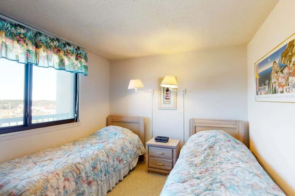 A bedroom with two beds and a nightstand between them.