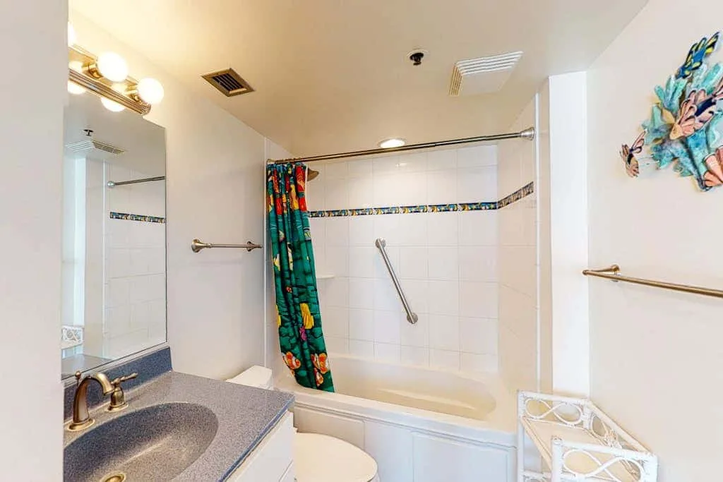 A bathroom with a bathtub, colorful shower curtain, and sink.