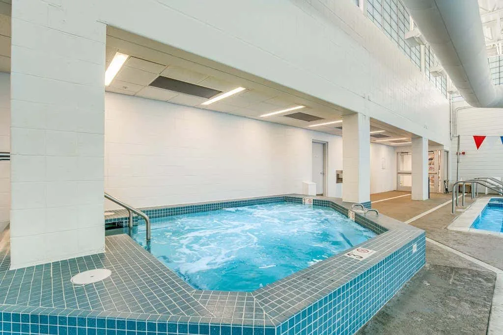 Indoor swimming pool with blue tile and a smaller pool in the background.