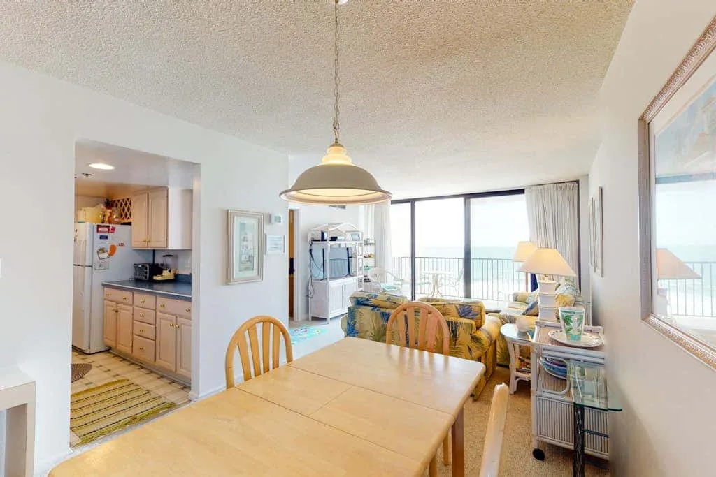 A dining area opens onto a living room with large windows overlooking the water.