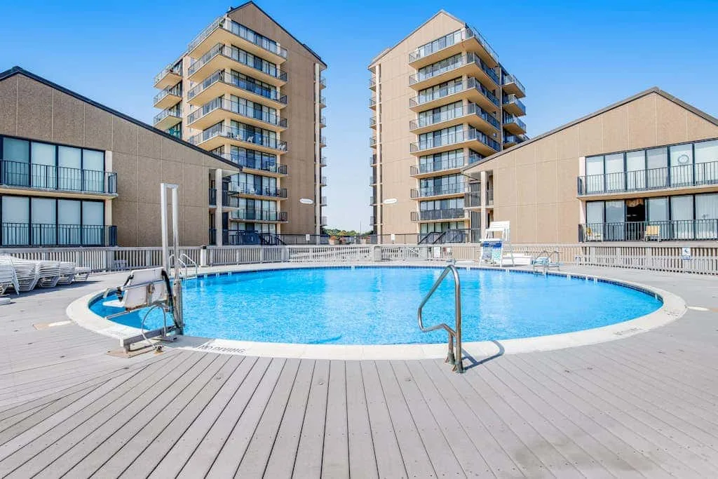 An outdoor swimming pool sits among several multi-story buildings.