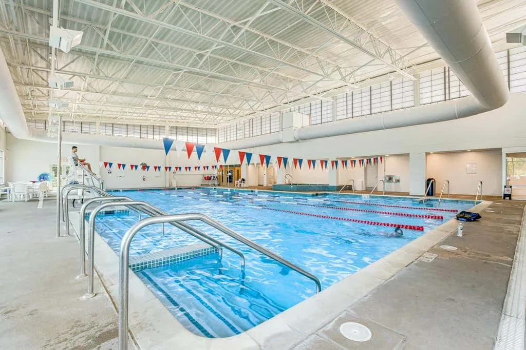 An indoor swimming pool with lane markers and colorful triangular banners.