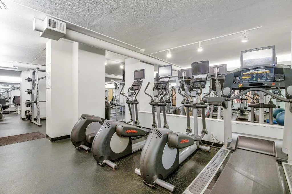 A gym with several elliptical machines and exercise equipment.