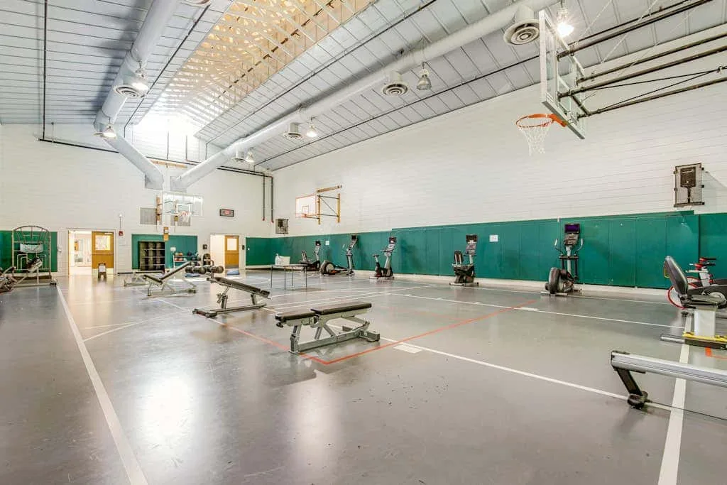 A gym with weight machines and benches arranged across the workout floor.