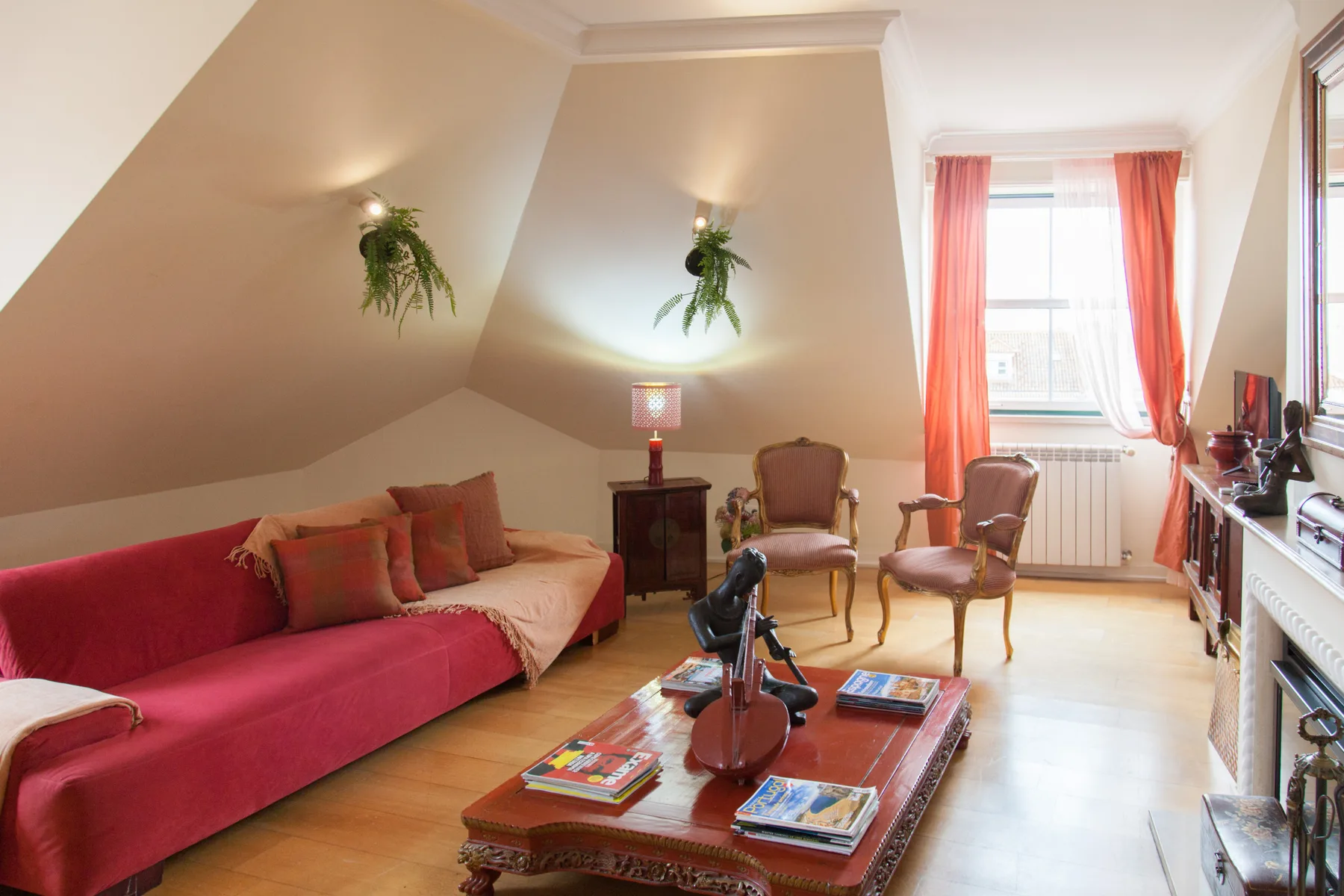 A bright living room has seating around a low wooden table, with a window at the far end.