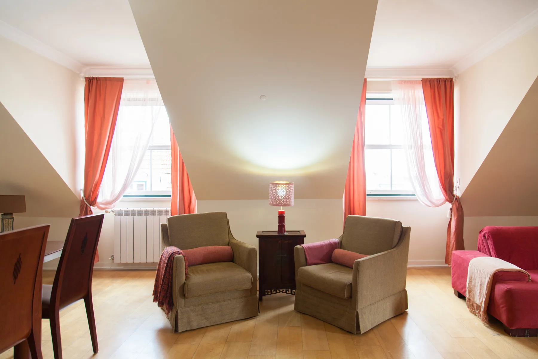 A sitting room with two armchairs, a small table, and bright windows.