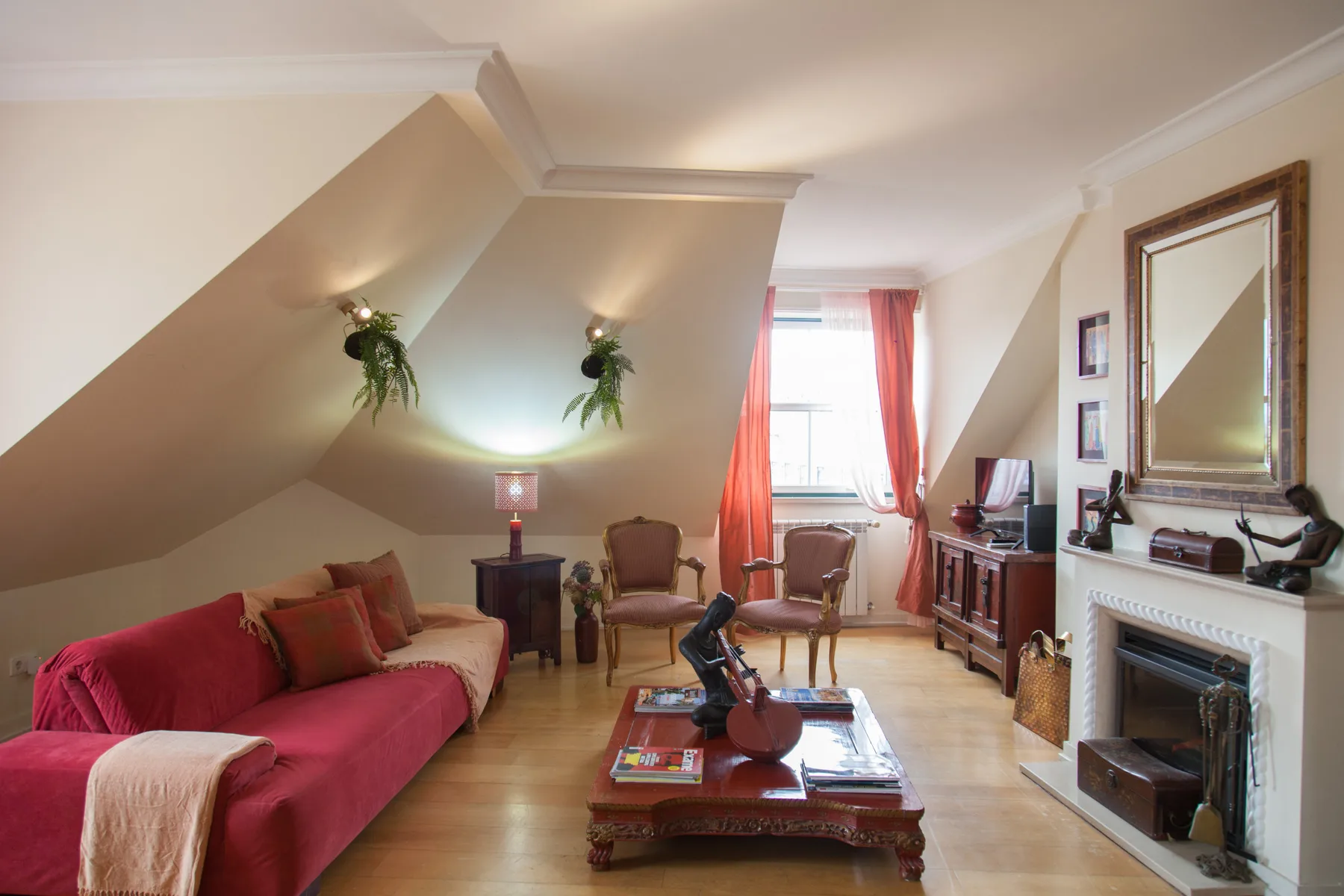 A living room with seating around a coffee table beneath a sloped ceiling.