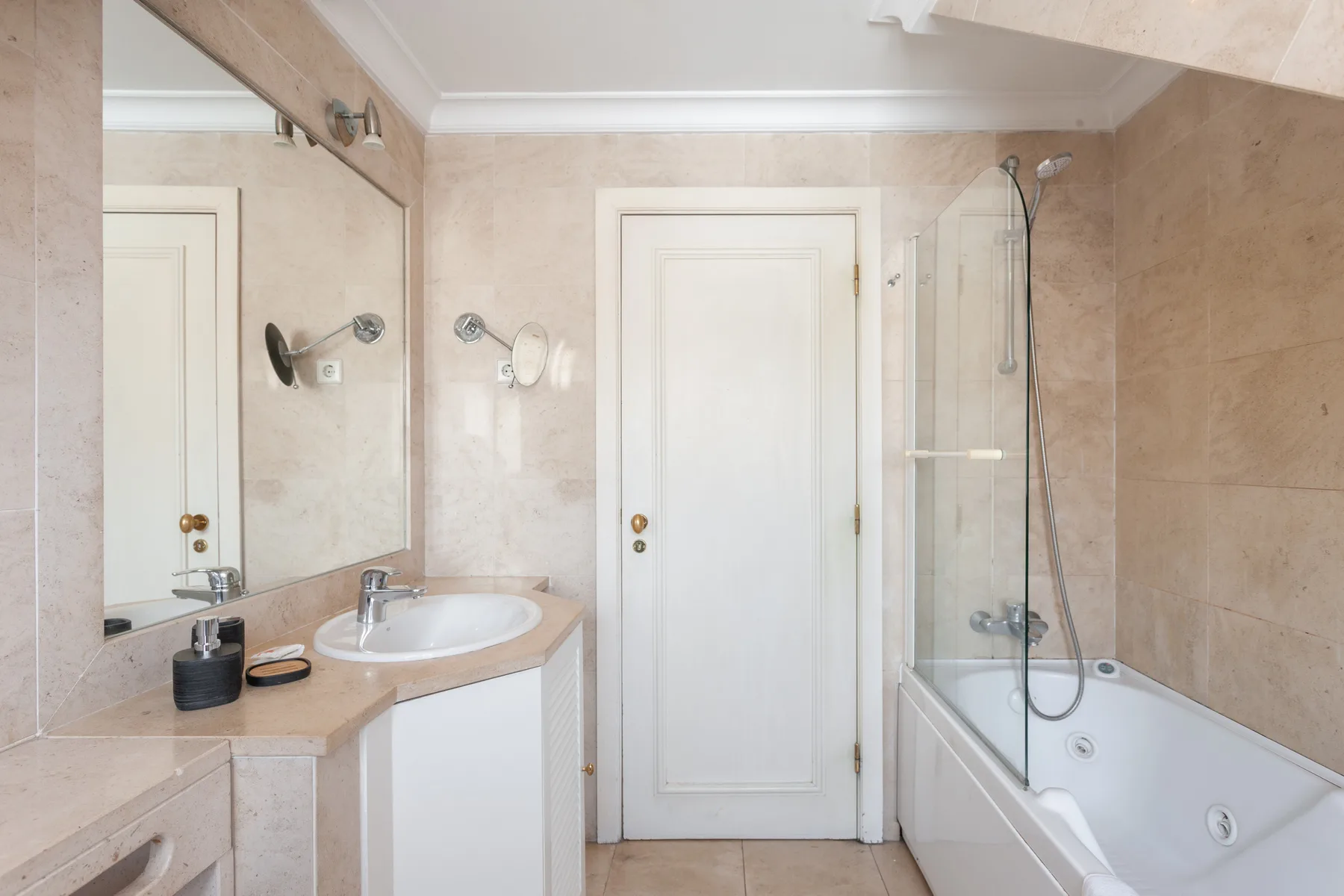 A bright bathroom with a sink, mirror, and bathtub with a shower.