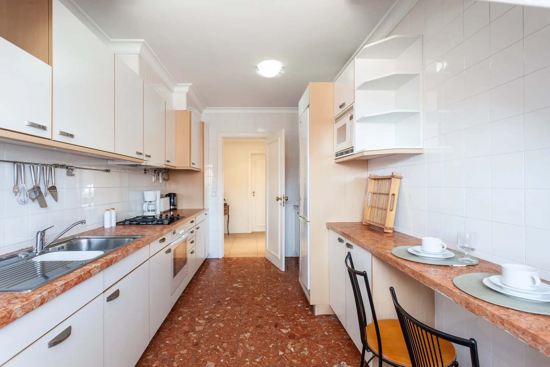 A narrow kitchen with counters along both sides and a dining table.
