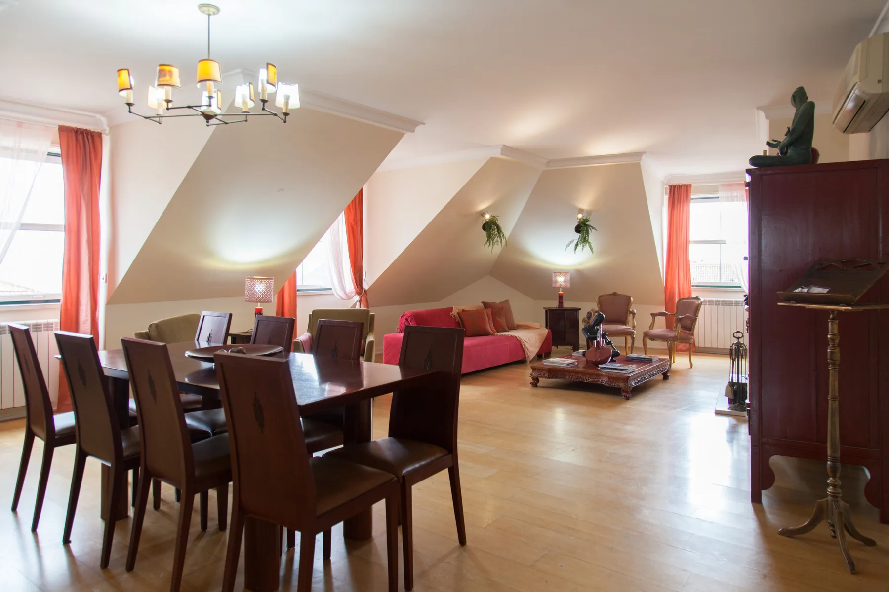 A spacious living and dining room with a red sofa and wooden dining table.