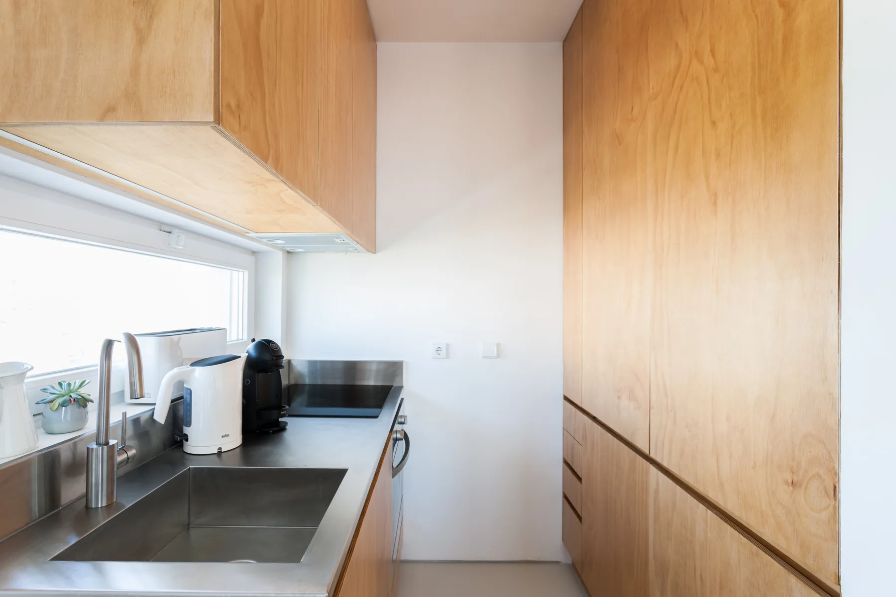 A compact kitchen with a countertop, appliances, and wood cabinetry.