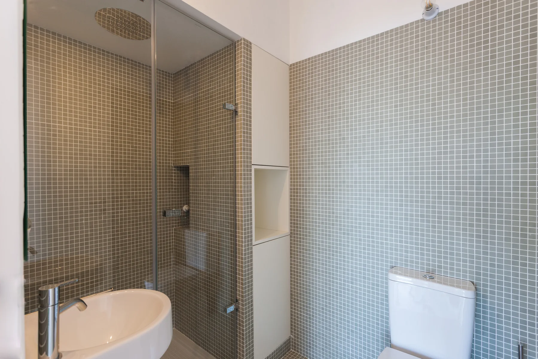 A tiled bathroom with a glass-enclosed shower and a sink.