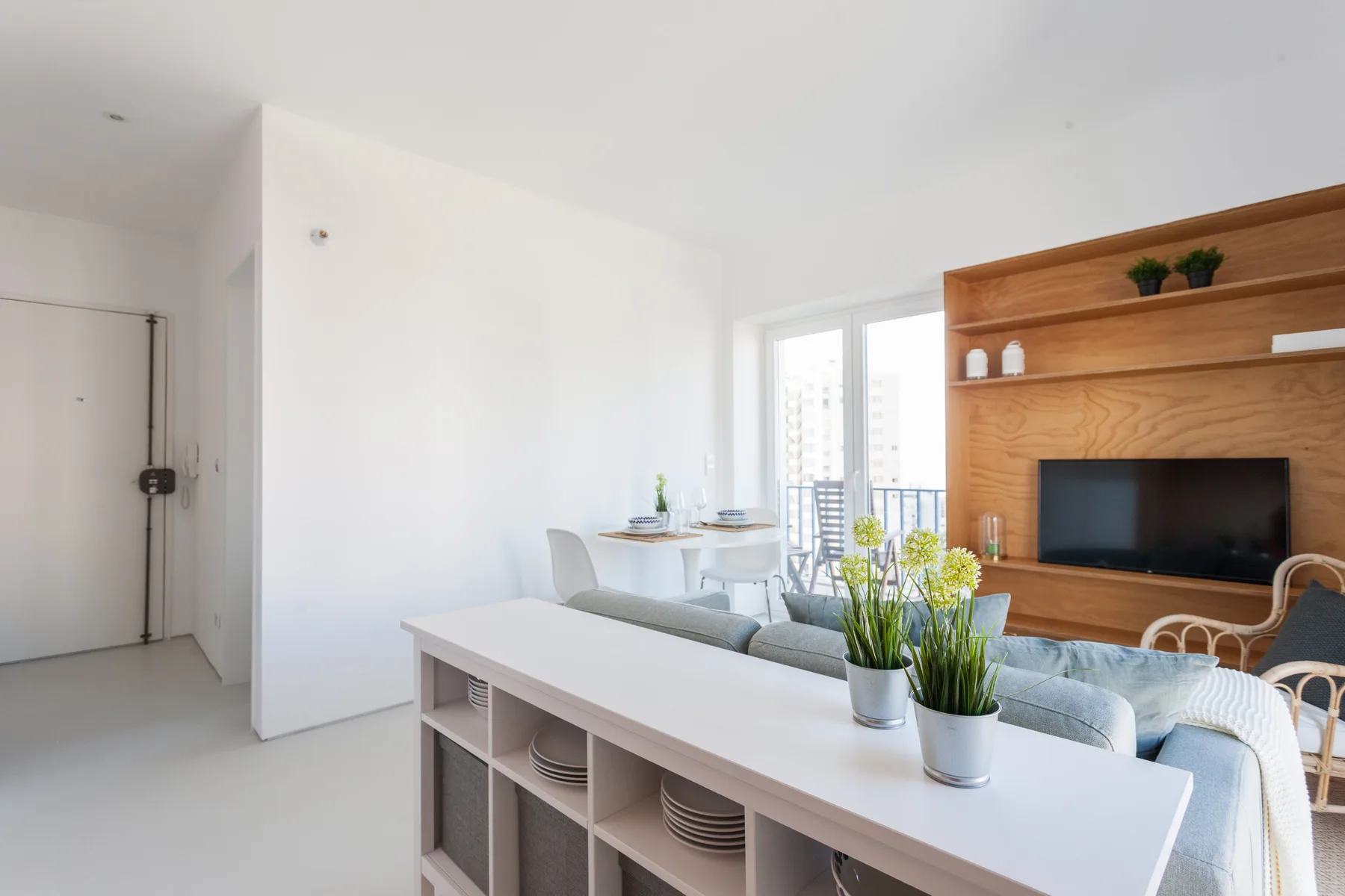 A bright living room with a dining area and a wooden entertainment wall.
