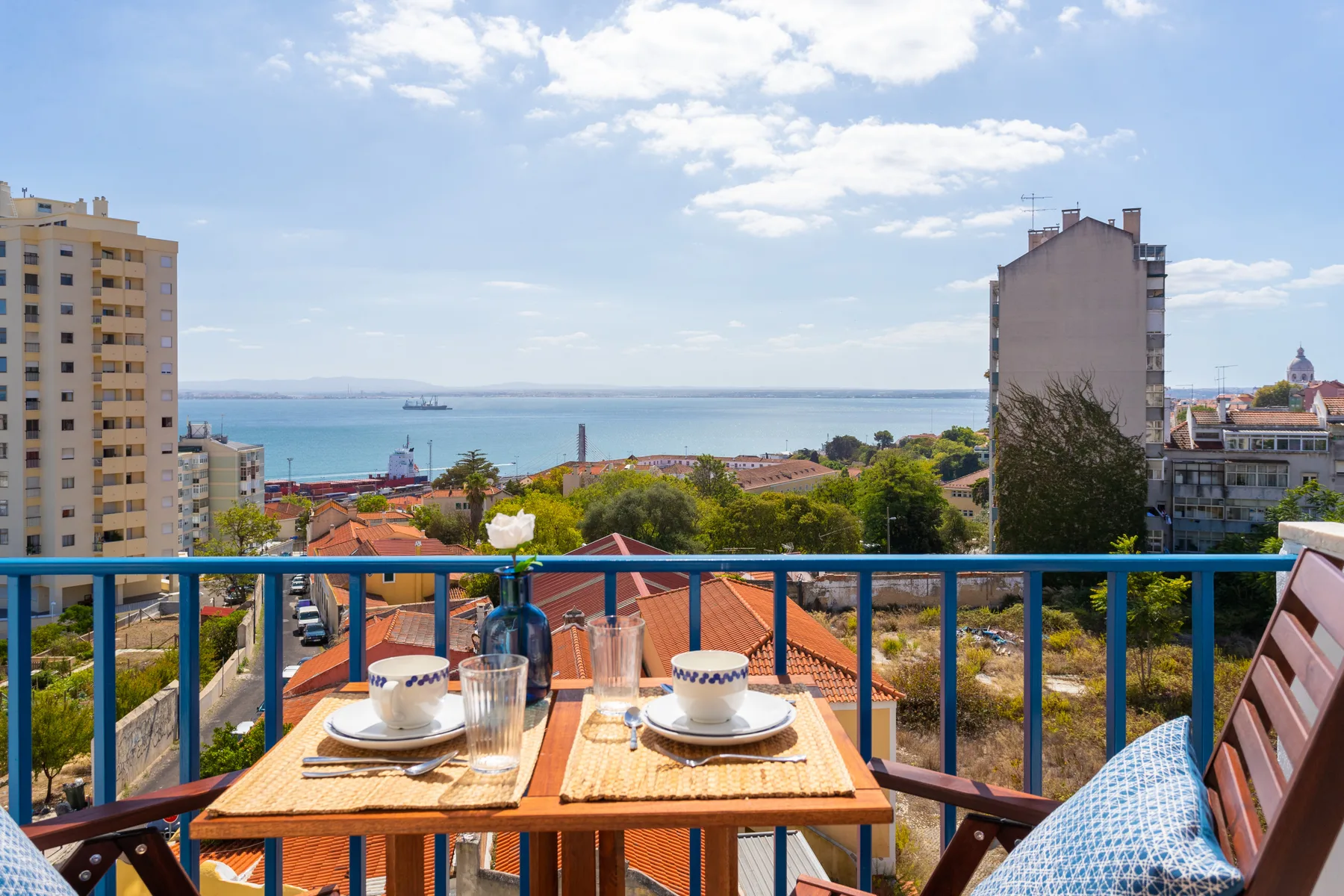 A balcony dining table overlooks the river and nearby rooftops.