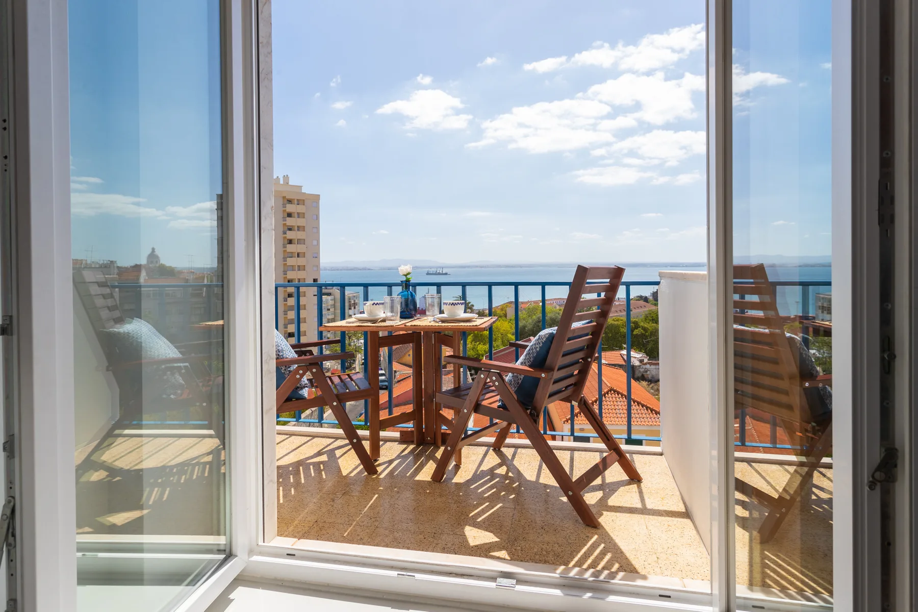 A balcony seating area overlooks nearby rooftops and the water.