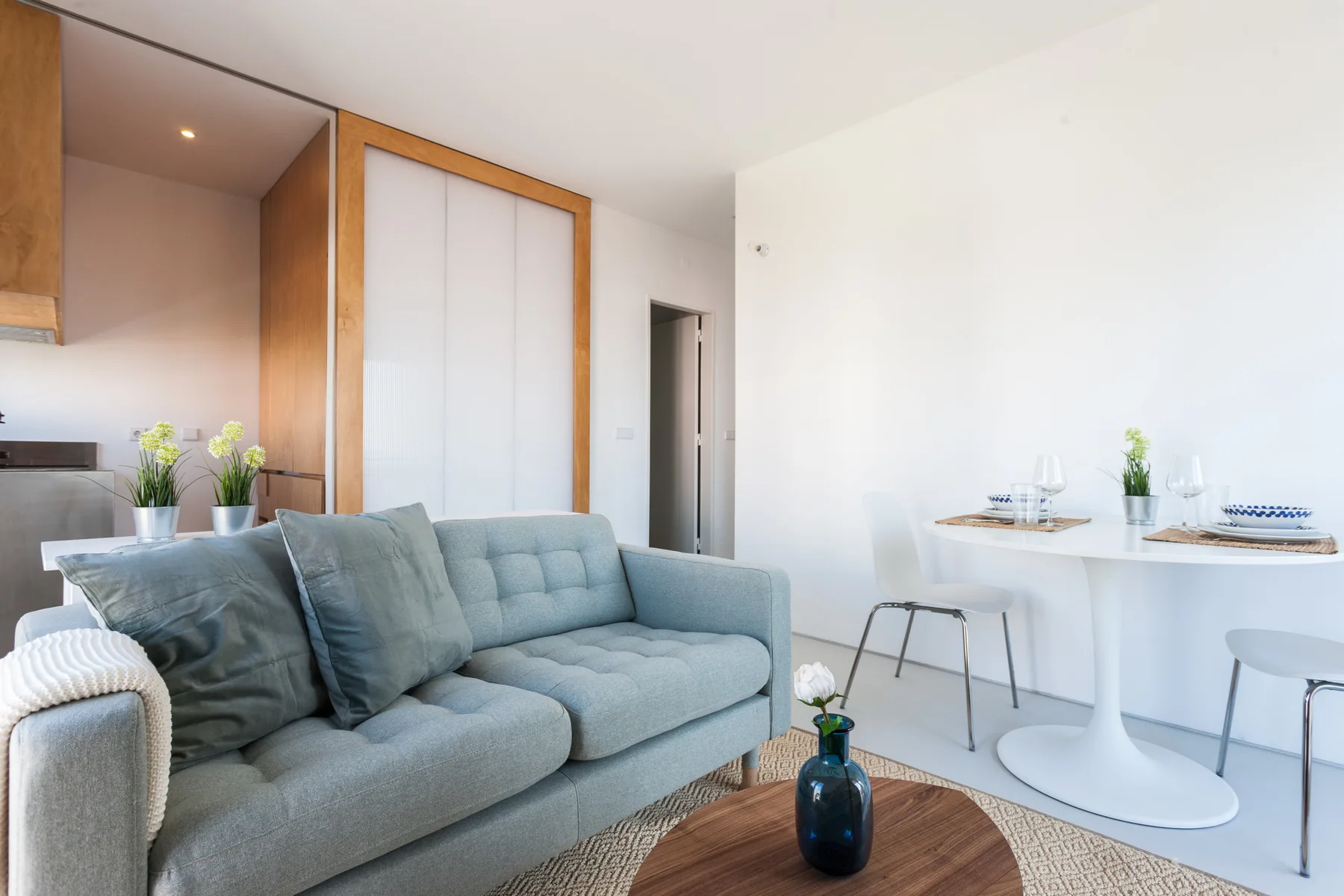 A bright living area with a gray sofa beside a small dining table.