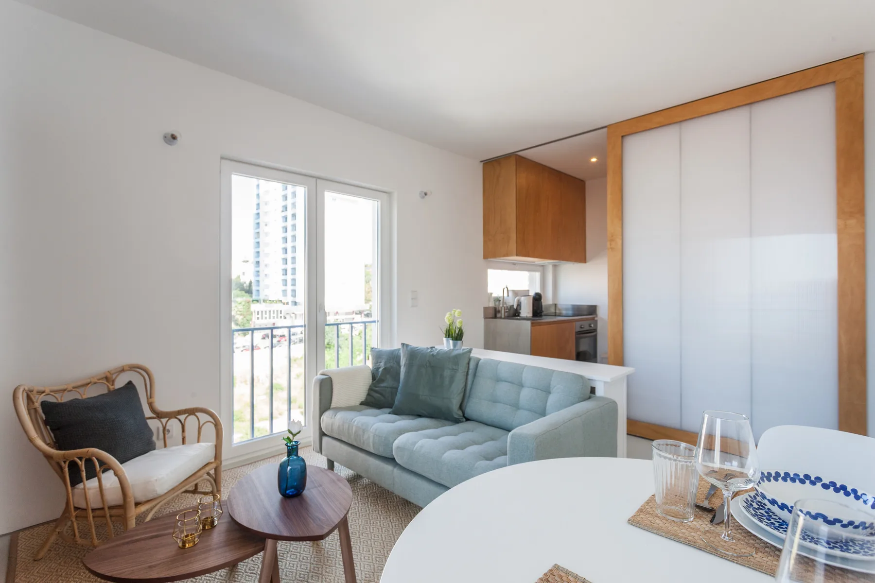 Living and dining area with seating, a round table, and balcony doors.