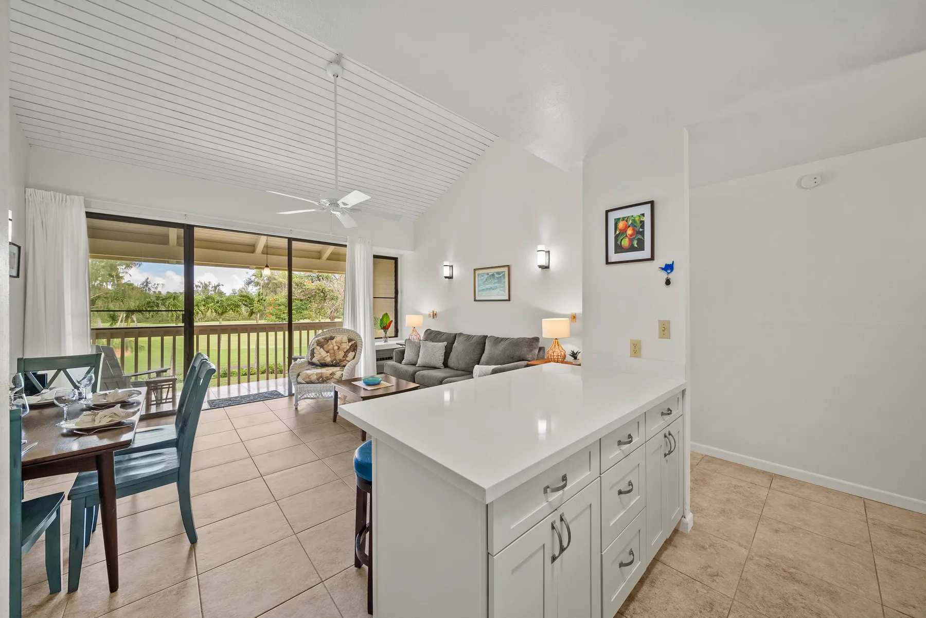 A bright open-plan kitchen and living area with a dining table by sliding glass doors.