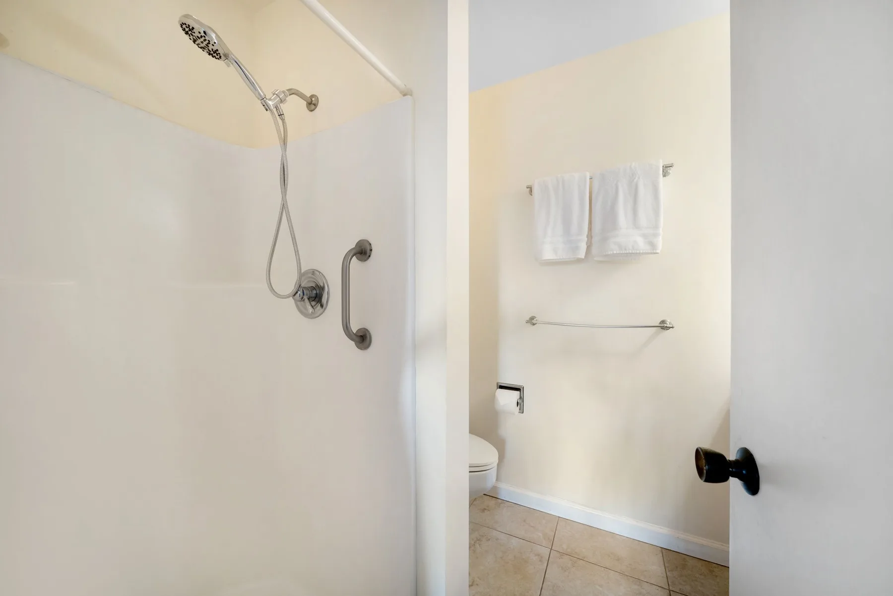 A bathroom shower area with a towel hanging on the wall.