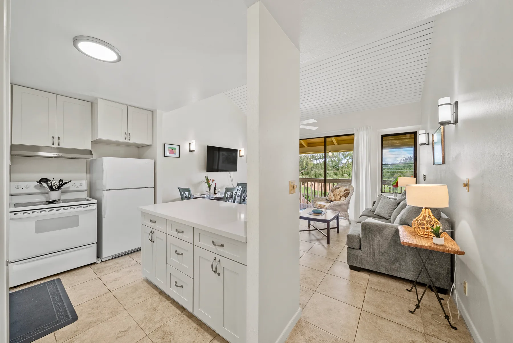 An open-plan kitchen and living area with a counter, seating, and large windows.