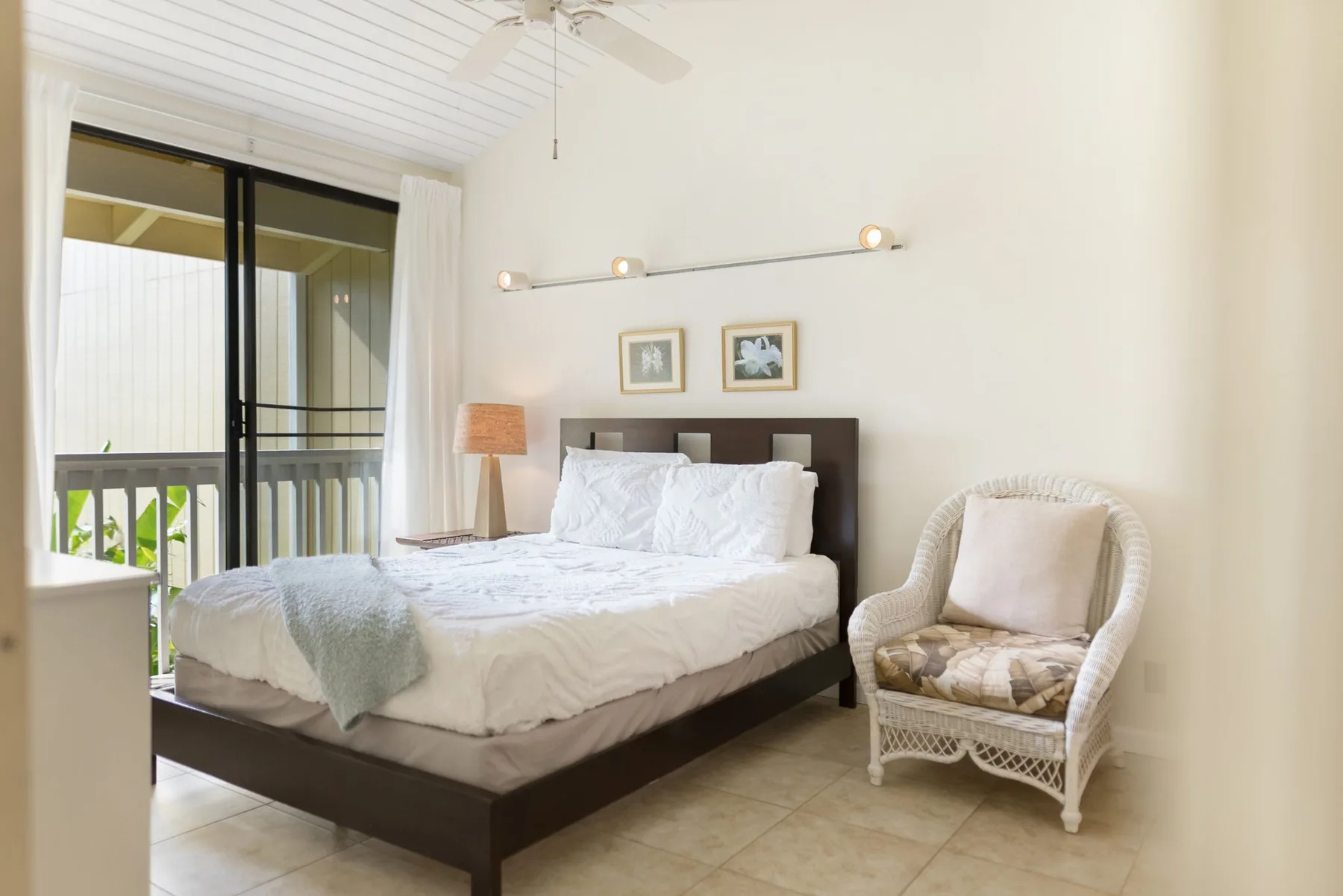 A bedroom with a bed, bedside lamp, and a sliding glass door to a balcony.