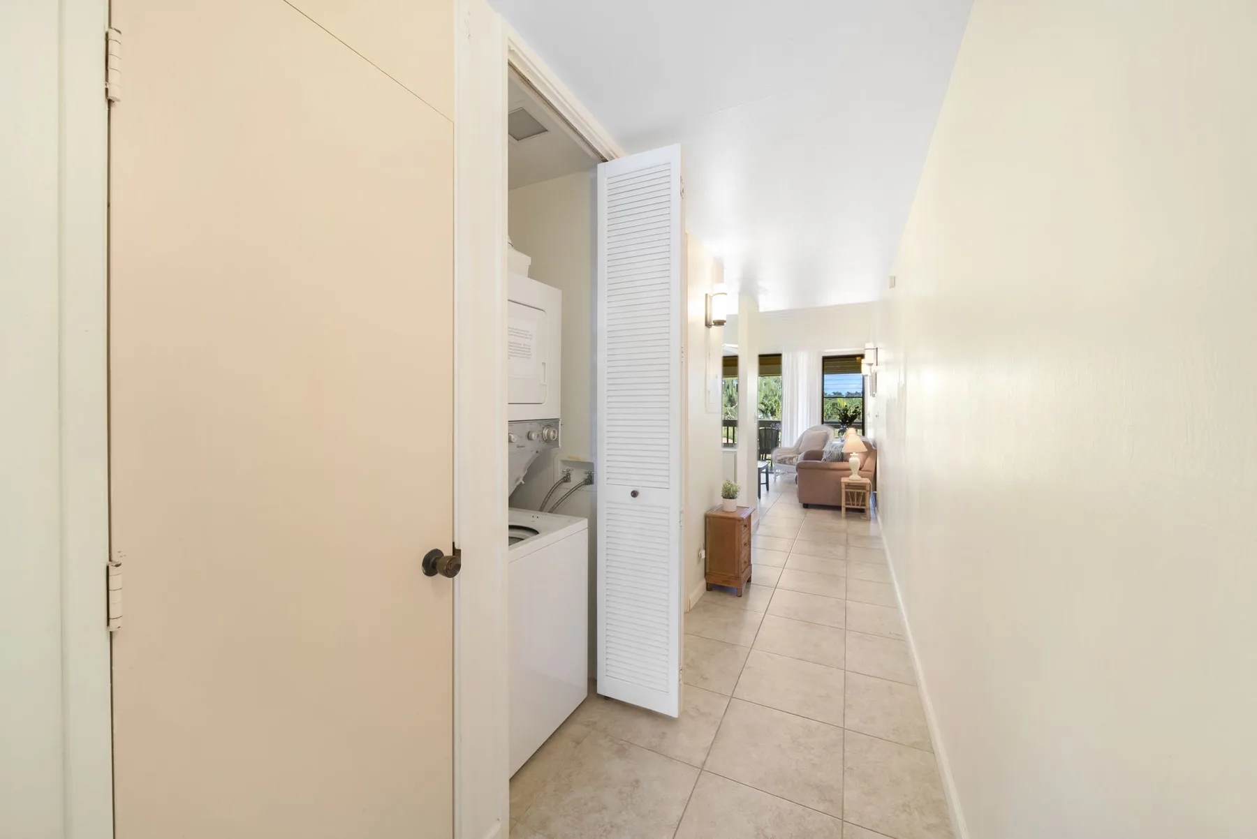 A tiled hallway leads toward a sitting area, with a laundry nook beside it.