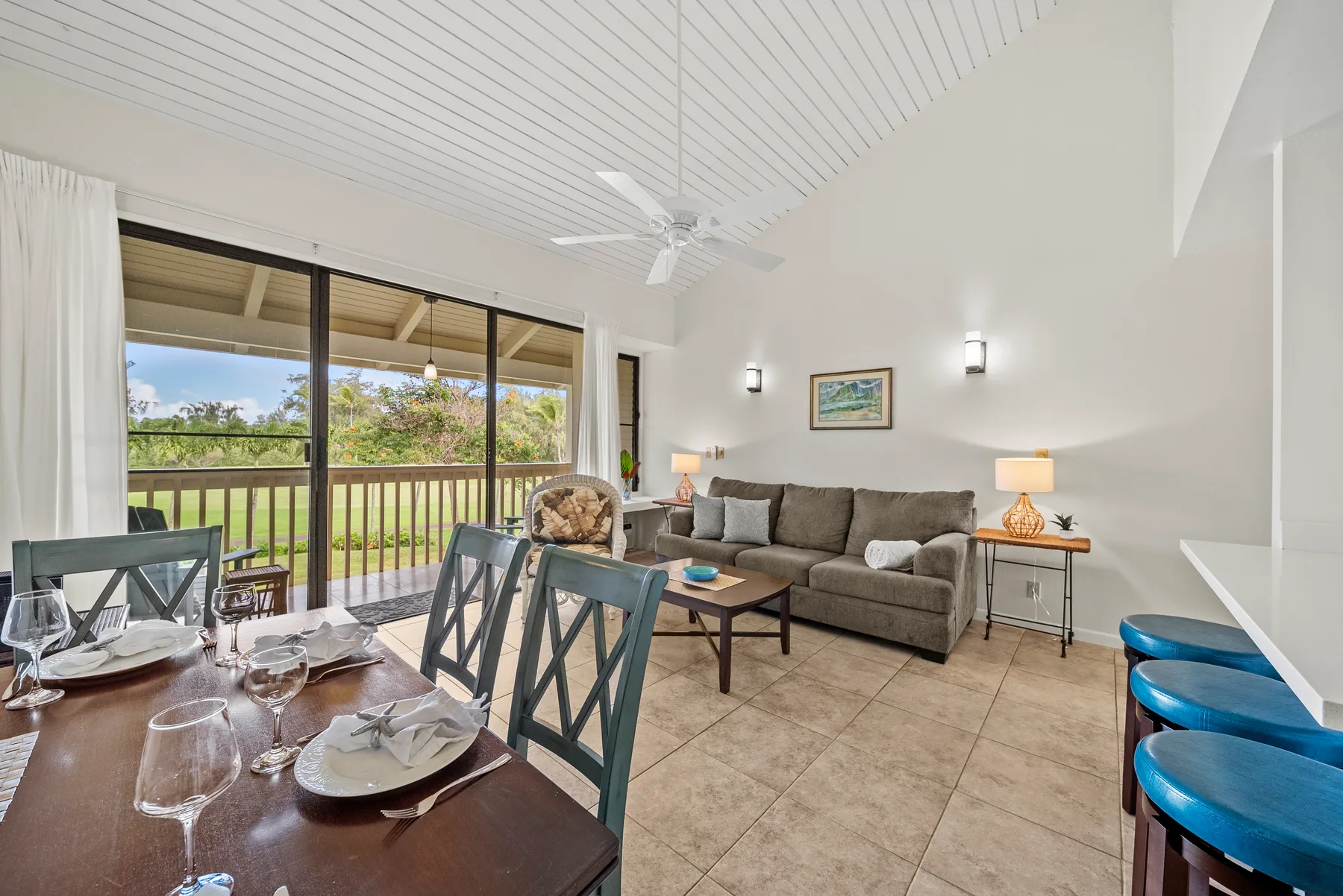 A bright living and dining area opens onto a balcony, with a sofa and dining table.