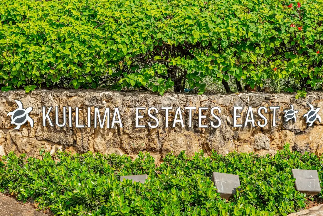 A stone sign reading “Kuilima Estates East” sits among green hedges.