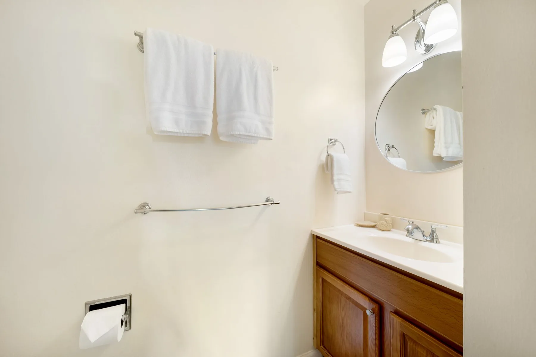 A bathroom with a sink vanity, mirror, and hanging towels.