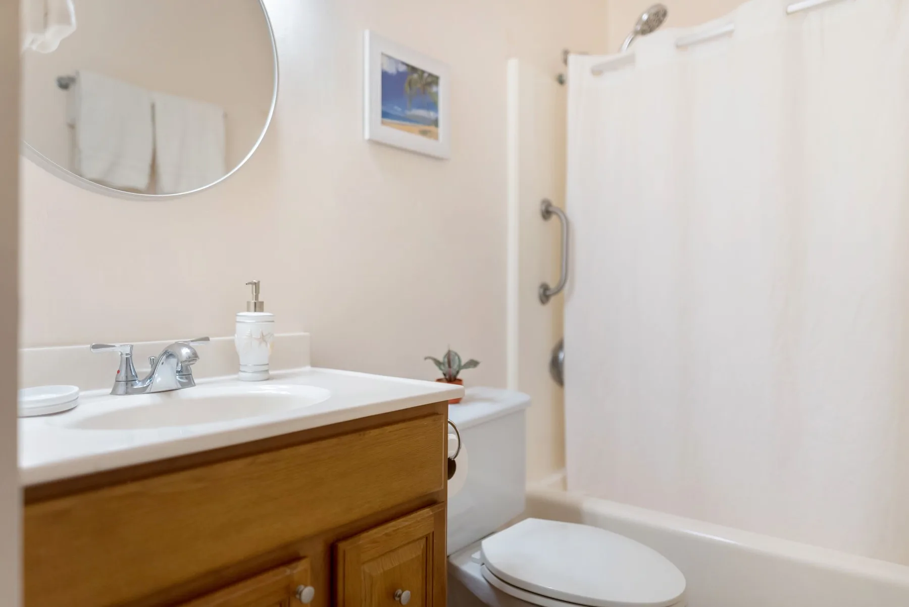A bathroom with a vanity, sink, toilet, and bathtub with a shower.
