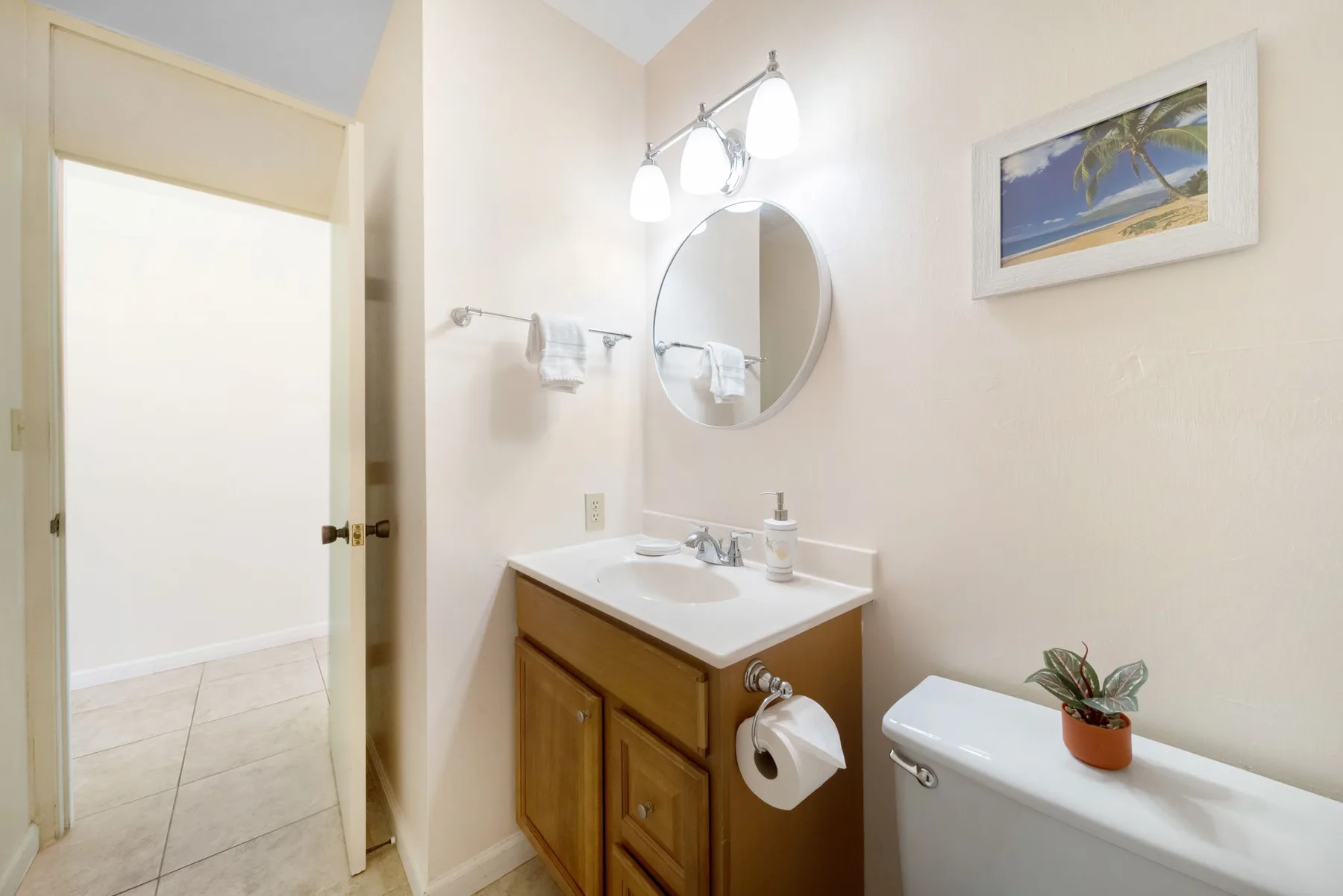 A bathroom vanity with a round mirror sits beside a toilet.