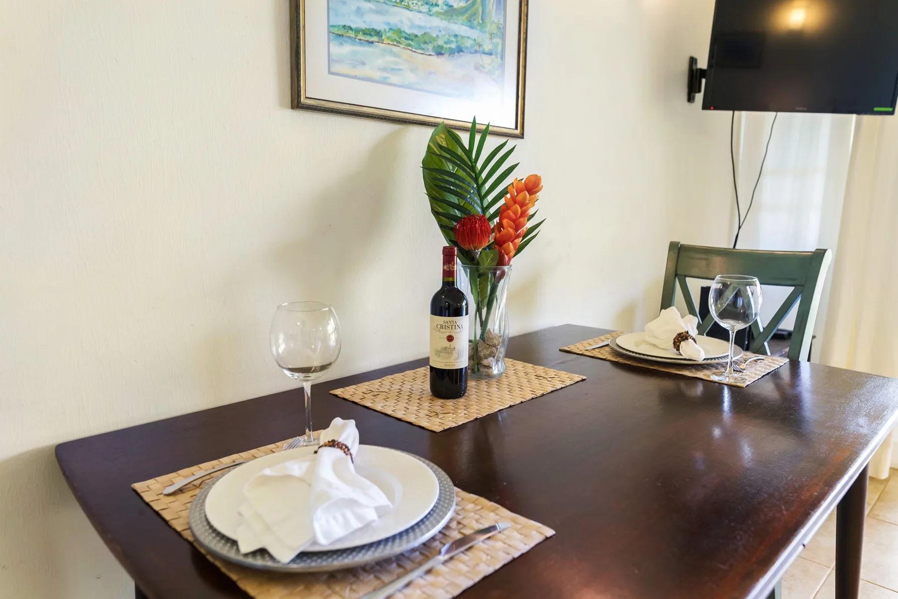 A dining table is set with plates and a small floral arrangement.