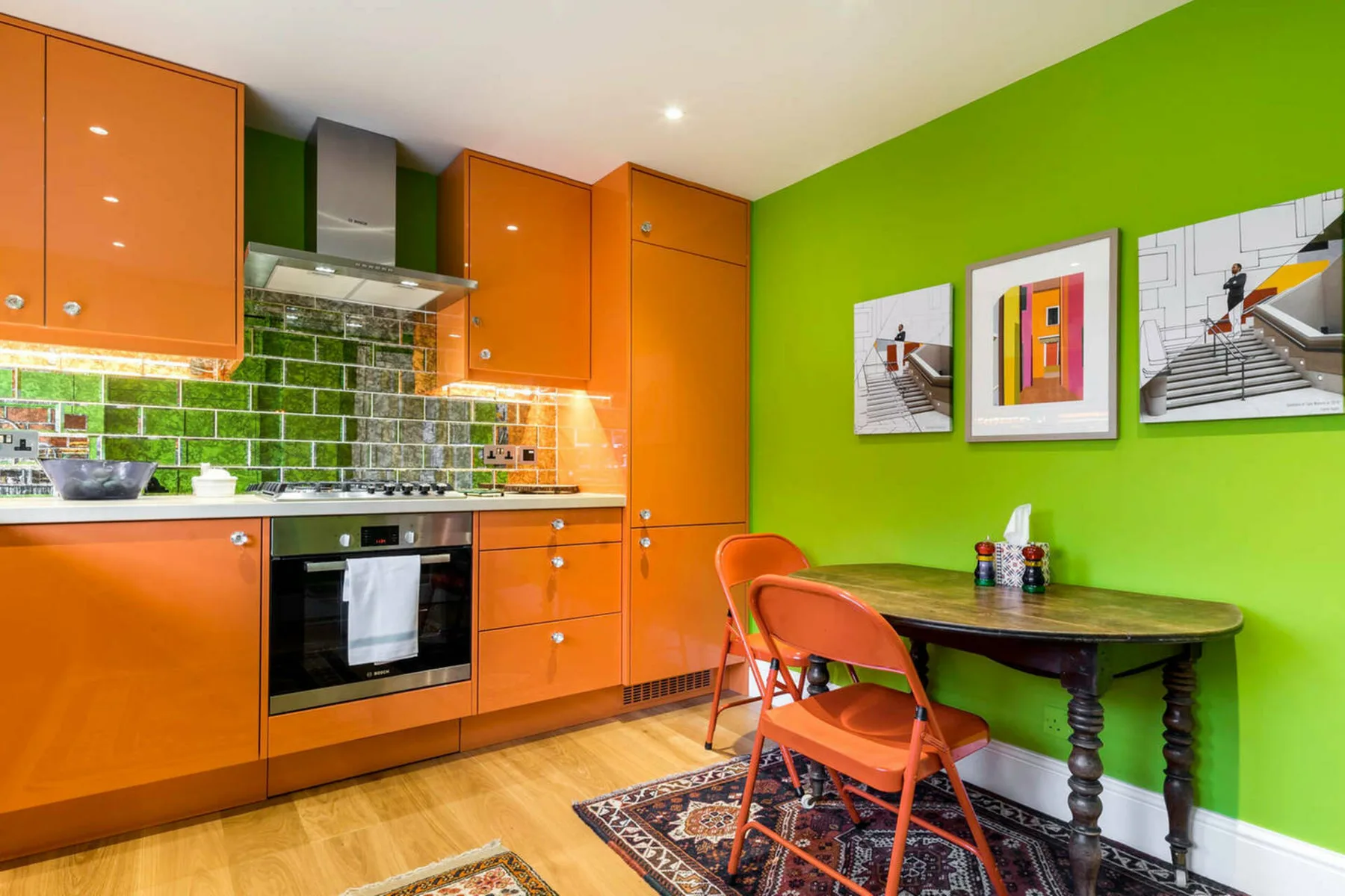 Una cocina colorida con gabinetes naranjas y una pequeña mesa de comedor.