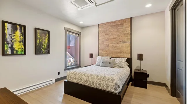 A bedroom with a bed against a wood-paneled wall and framed artwork.