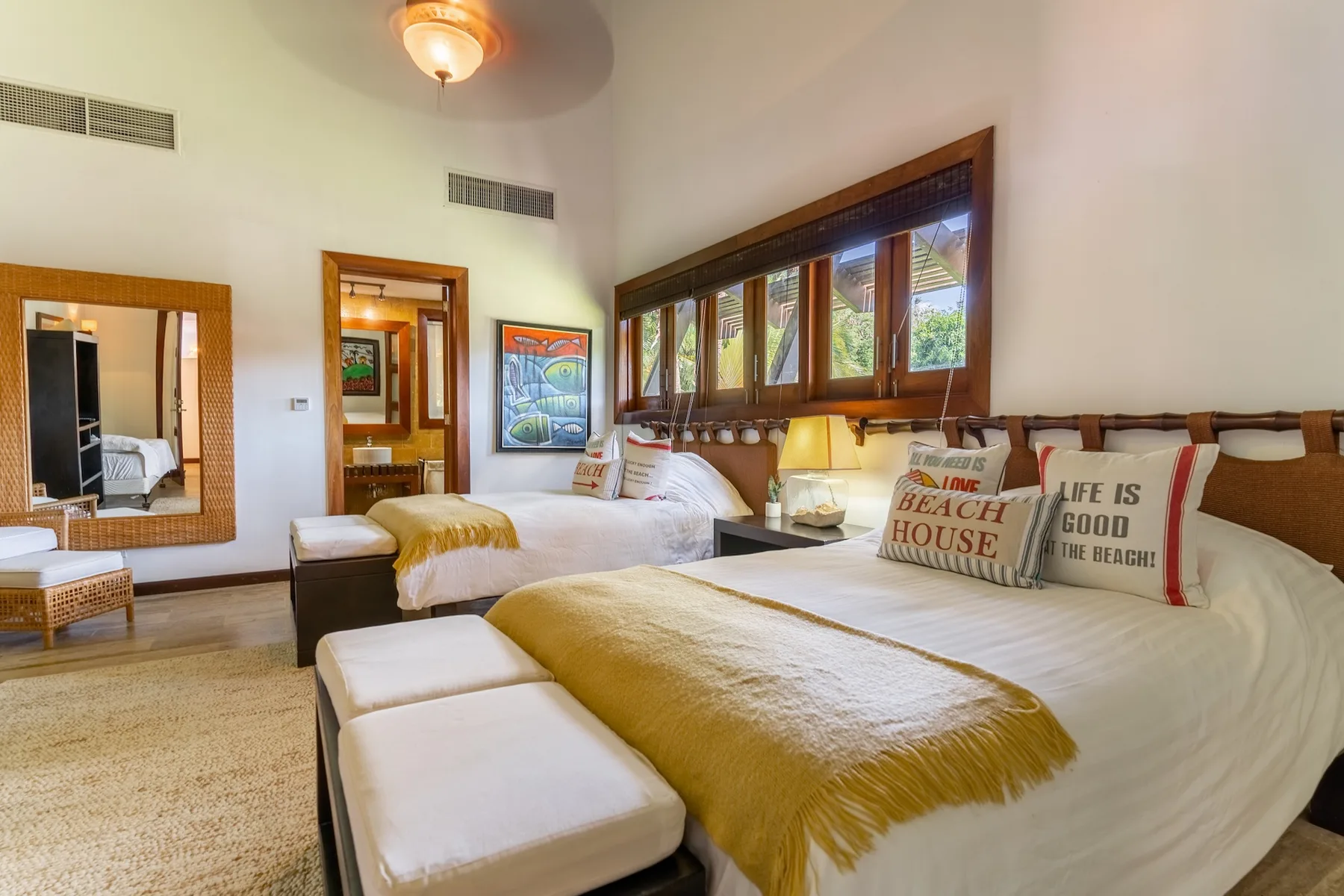 A bedroom with two beds, a window seat, and wooden-framed windows.